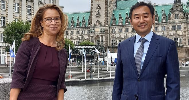Carola Veit und Ki-hong Jung posieren vor dem Hamburger Rathaus für ein Foto.