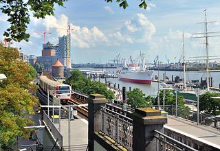 Blick auf Hamburg von der UBahn Landungsbrücken aus. Einfahrende U-Bahn, Elbphilharmonie und Elbe im Hintergrund.
