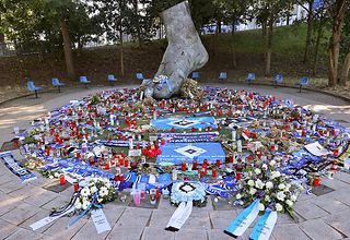 Bronze-Fuß von Uwe Seeler umrahmt von zahlreichen Blumen, Kerzen und Kränzen - vorwiegend in den Farben des HSV weiß-blau