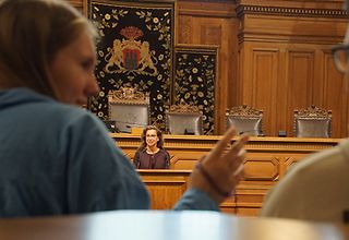 Präsidentin Carola Veit spricht im Plenarsaal vor den Jugendlichen von Jugend im Parlament, im Vordergrund gestikuliert ein Mädchen mit ihrem Sitznachbarn.