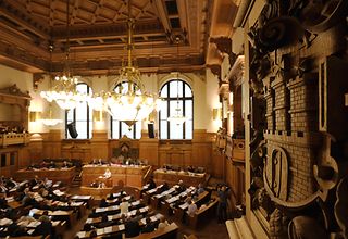 Blick von oben in den vollbesetzten Plenarsaal. Im Vordergrund ist das Hamburger Wappen zu sehen.