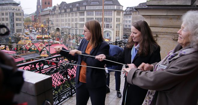Mareike Engels, Melanie Leonhard und eine Vertreterin von Terre des Femmes ziehen an der Kordel zum Hissen der Flagge.