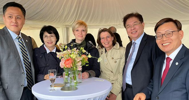 Gruppenfoto mit Südkoreanern und Bürgerschaftsabgeordneten Anke Frieling (CDU) und Olga Petersen (AfD), die um einen Stehtisch herumstehen, alle lächeln in die Kamera.