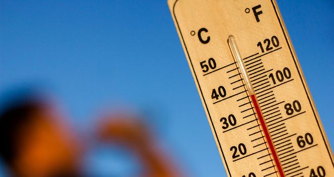 Ein Thermometer zeigt Temperaturen um die 38 Grad Celsuis an. In Hintergrund trinkt ein Menschen aus einer Flasche.
