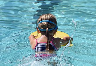 Ein Mädchen schwimmt mit einem Schwimmbrett.