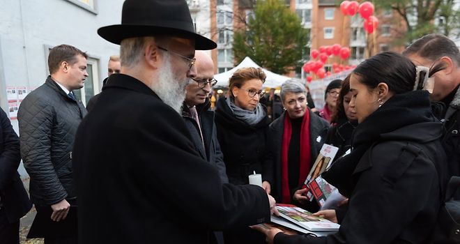 Mehrere Personen, darunter Carola Veit, Dr. Peter Tschentscher und Shlomo Bistritzky, unterhalten sich. Sie halten Fotos der Hamas-Geiseln sowie Kerzen in den Händen.