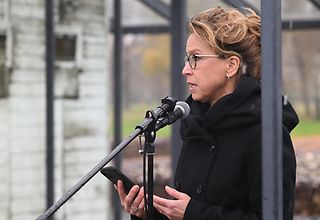 Carola Veit steht am Mikrofon an der KZ-Gedenkstätte Neuengamme.