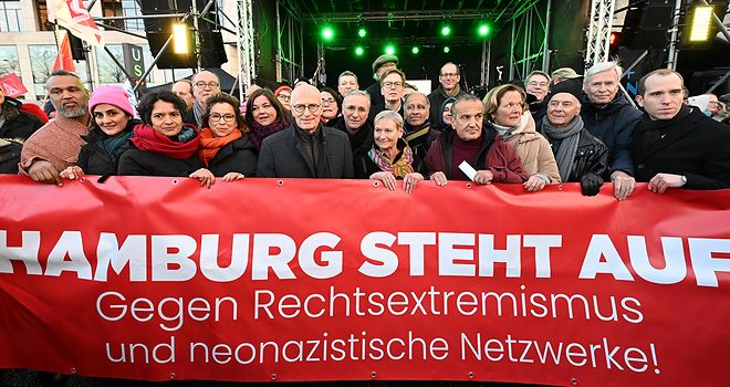 Viele Personen halten ein großen roten Banner in den Händen mit der Aufschrift „Hamburg steht auf. Gegen Rechtsextremismus und neonazistische Netzwerke!