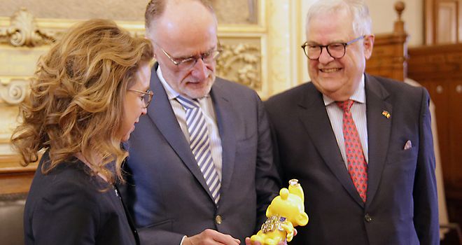Botschafter Geert Muylle überreicht Präsidentin Carola Veit einen gelben Schlumpf.