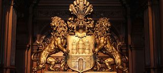 Das Staatswappen von Hamburg als goldenes Ornament im Großen Festsaal des Rathauses.